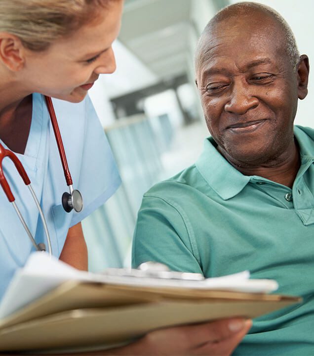 Picture of a man smiling when reviewing documents with a medical professional