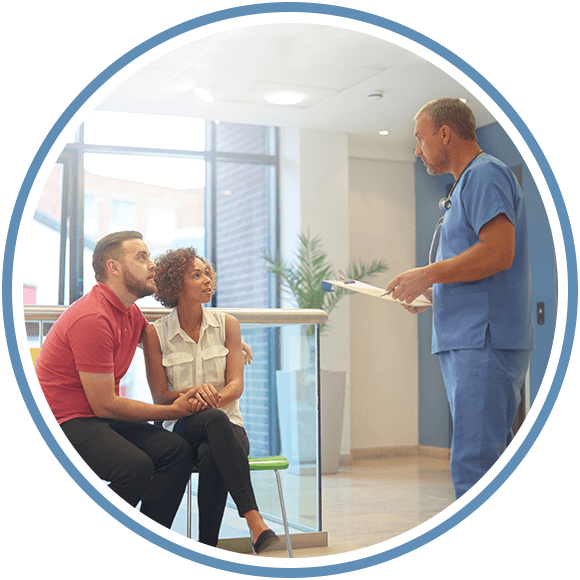 Picture of a medical professional speaking to a man and a woman sitting down